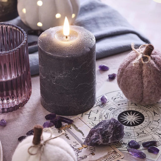 Candle, pumpkins, and crystals on a table with astrological symbols