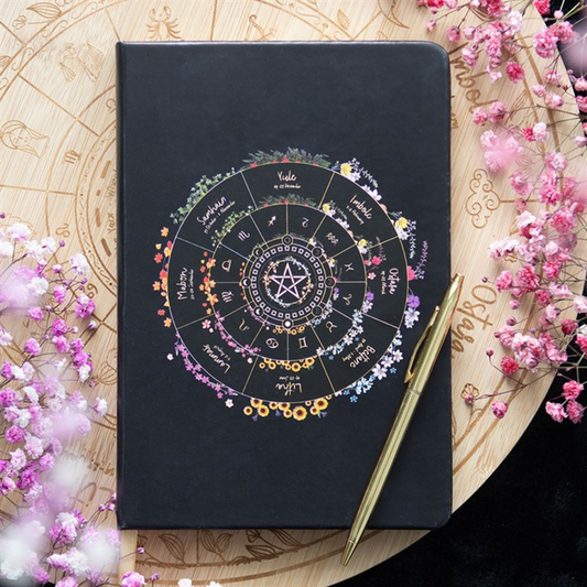 Black notebook with celestial design on a decorative background with flowers